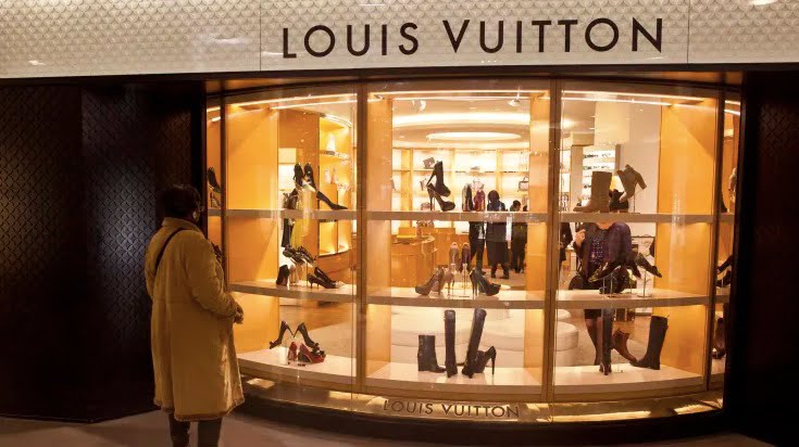 People line up as they wait to get in the Louis Vuitton shop on