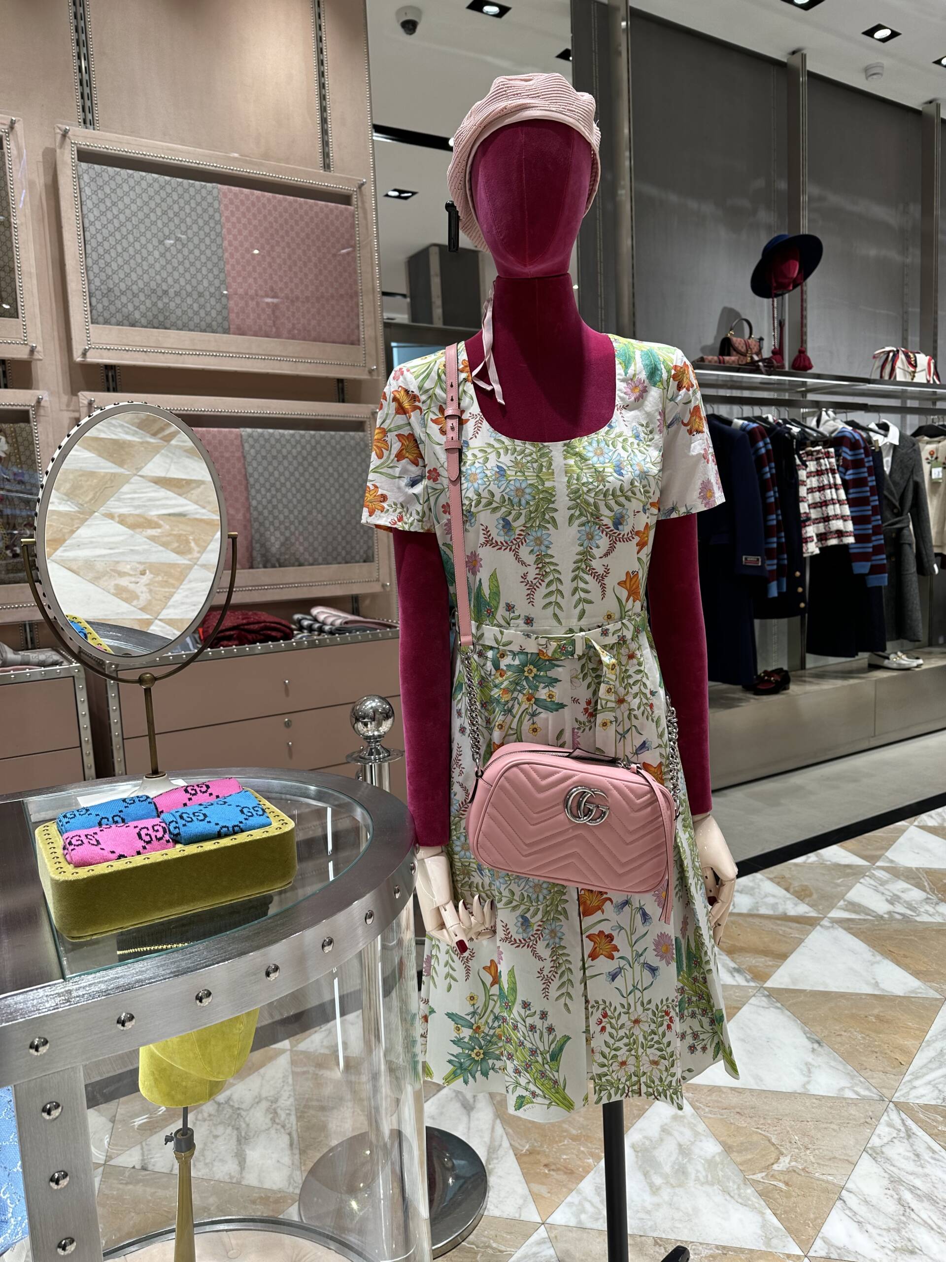 A mannequin wearing a Gucci dress and pink beret and pink leather crossbody handbag at the outlet in Paris.