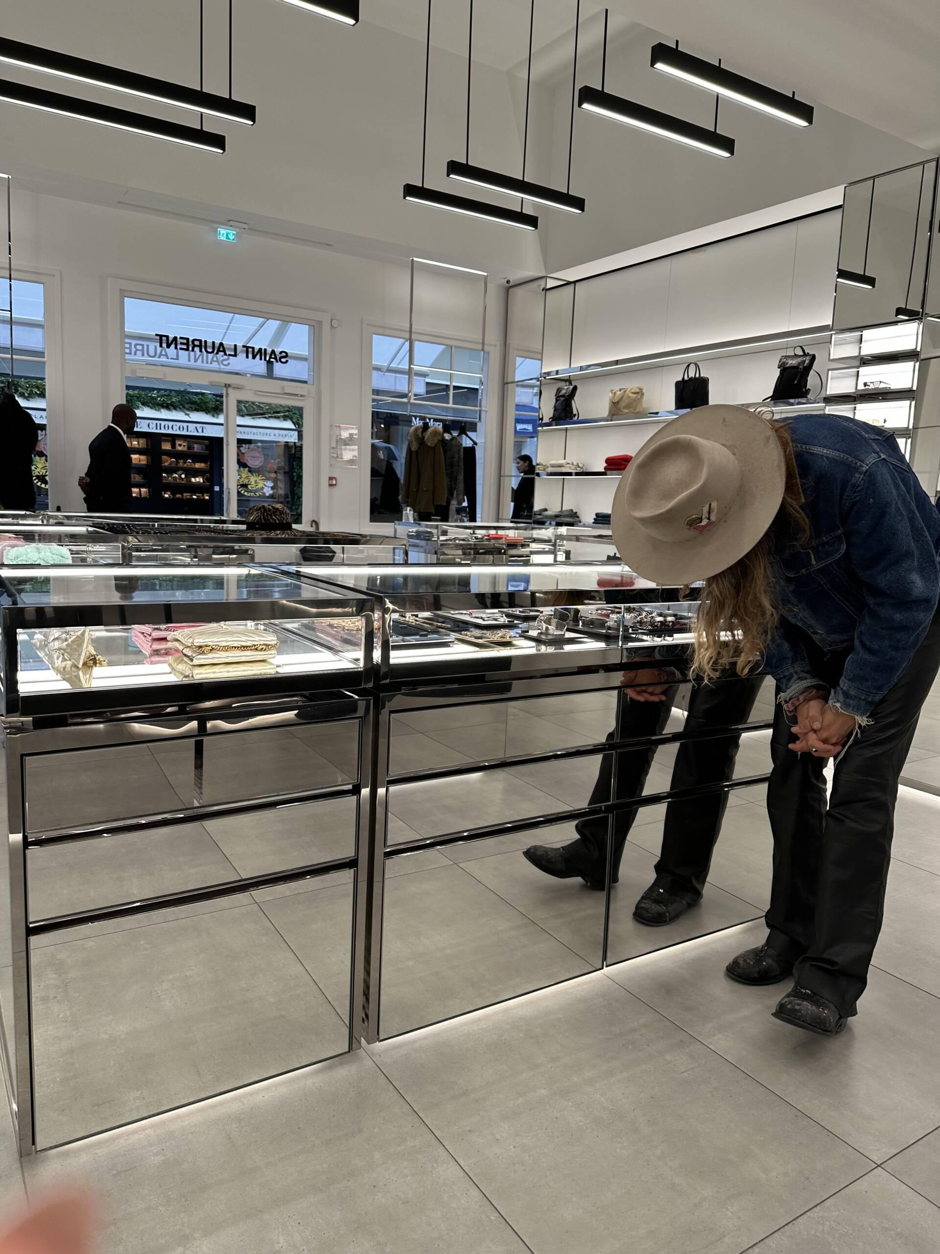 Man browsing at small leather goods at Saint Laurent YSL outlet in Paris.
