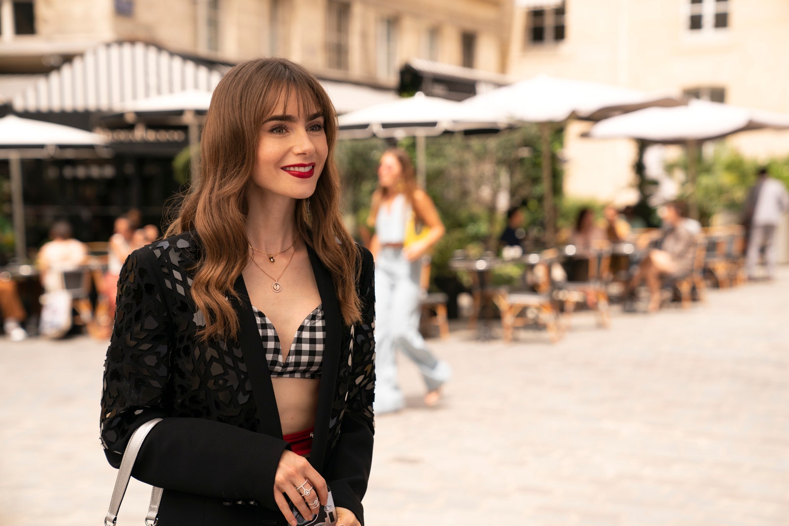 Emily in Paris Season 3 wearing a Barbara Bui Black blazer with a black and white gingham bandeau from Livy Studio in a outdoor Paris scene