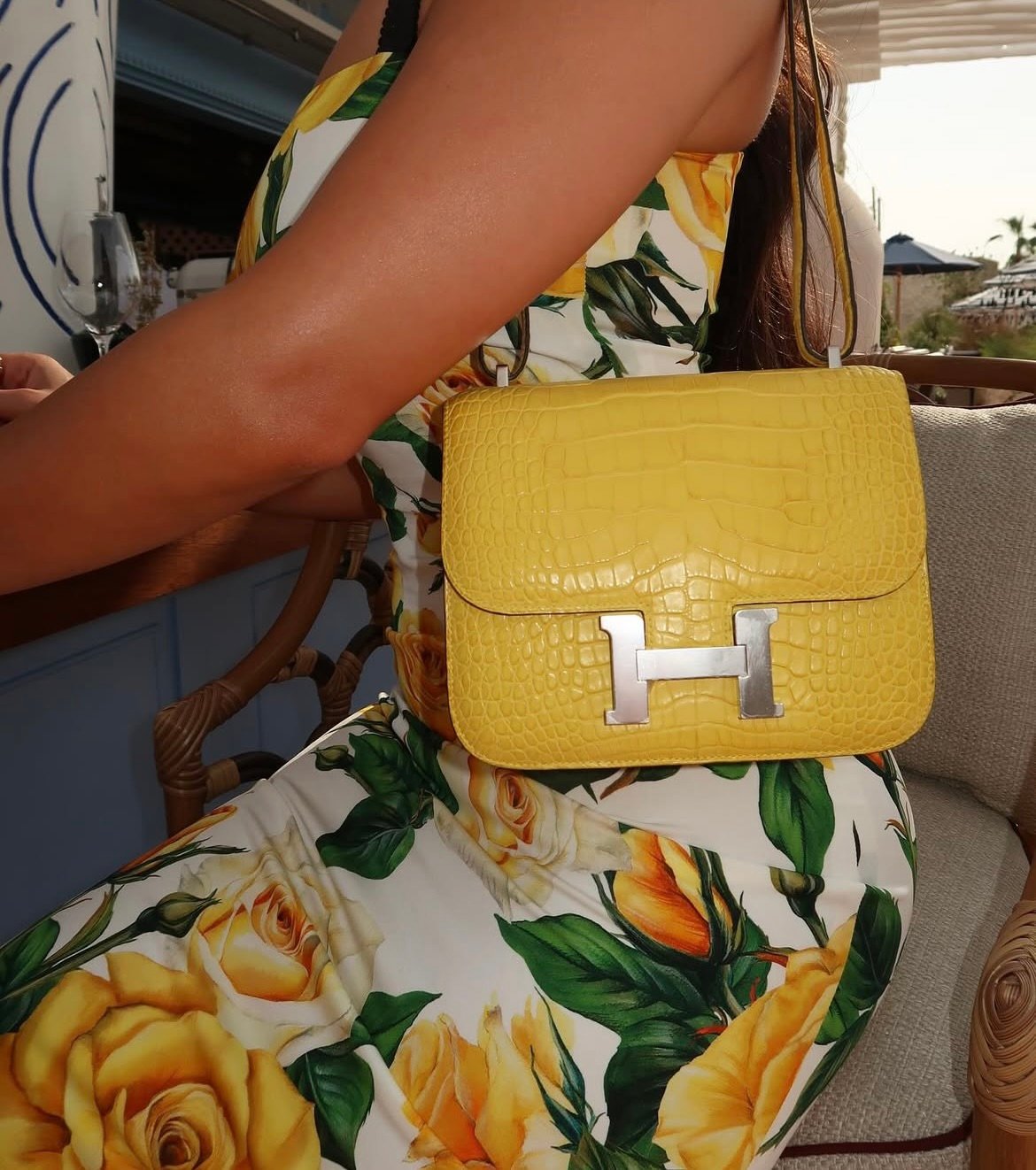 woman in floral dress wearing a yellow croc hermes constance 18